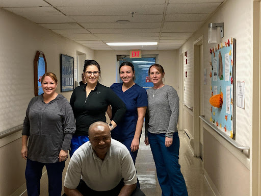 A cheerful group of healthcare workers poses for a photo in the hospital hallway.