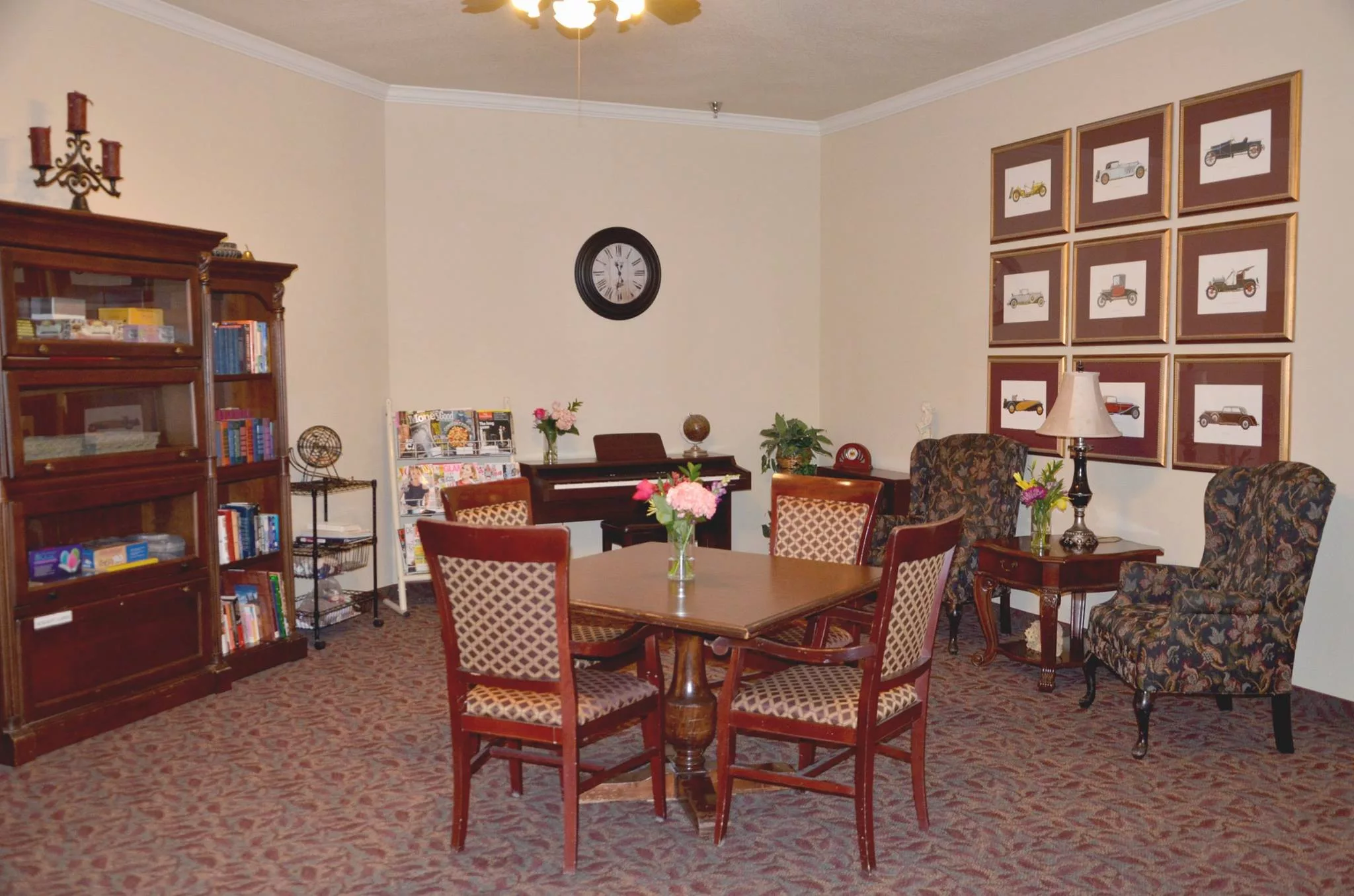 A cozy living room with a round table, chairs, and a bookshelf.