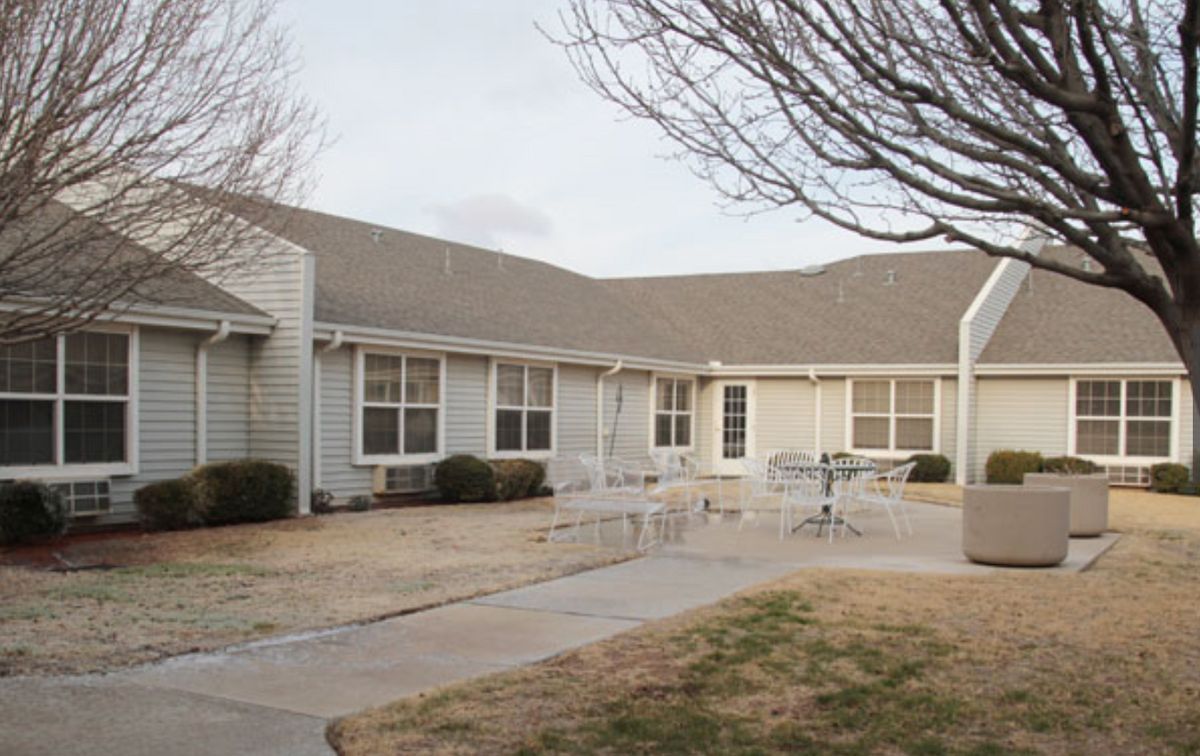 A residential building with a patio and outdoor furniture in the yard.