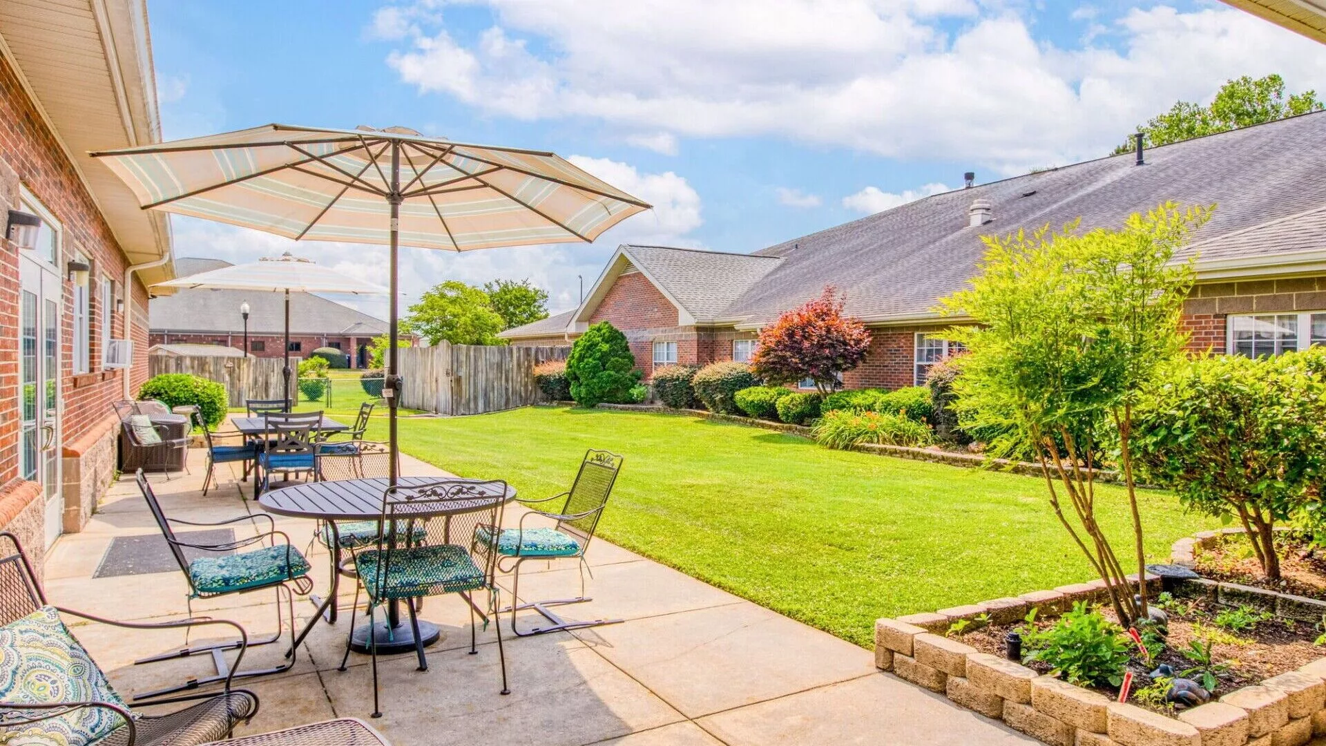 A beautifully maintained backyard with patio seating and lush green lawn.