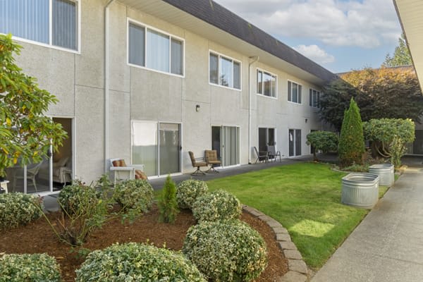 A two-story apartment building with a well-maintained lawn and garden area.