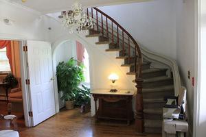 A cozy interior with a curved staircase, chandelier, and elegant decor.