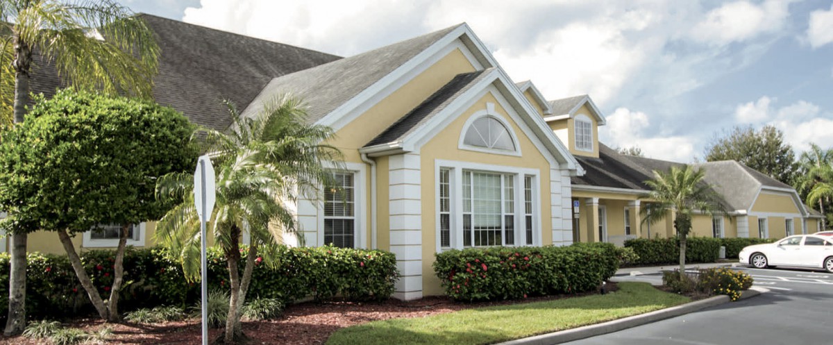 A suburban residential house with a yellow exterior and well-maintained landscaping.