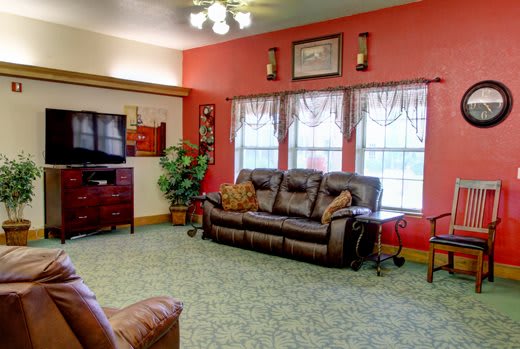 A cozy living room with a brown sofa, red walls, and a television.