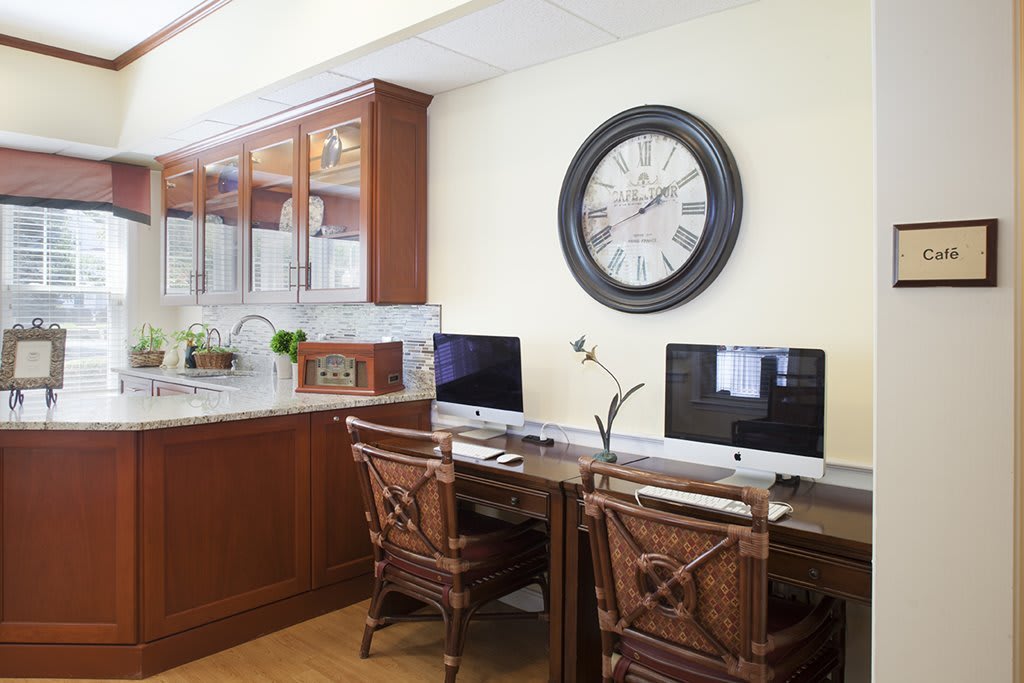 A stylish home office setup with two computers on wooden desks under a large wall clock.