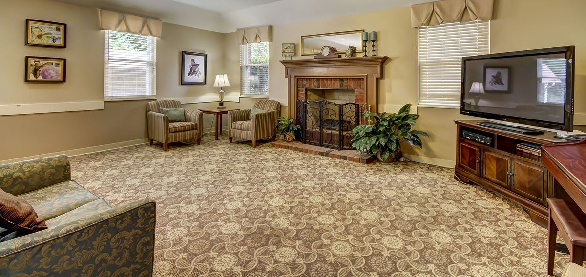 A cozy living room with a patterned carpet and a fireplace.