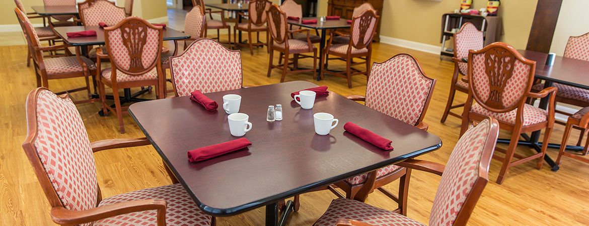 A dining table set up with red napkins and coffee cups, ready for guests in a restaurant.