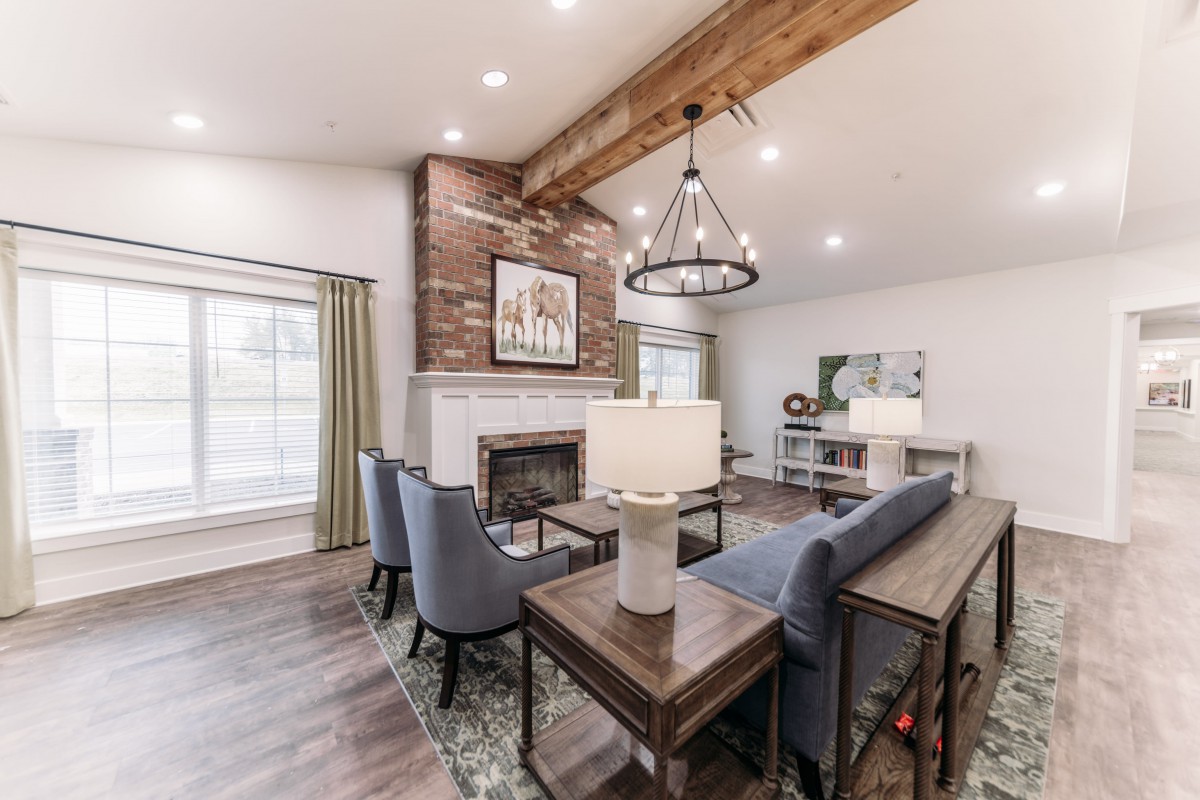 A modern living room featuring a large fireplace, wooden beam ceiling, and stylish furniture.