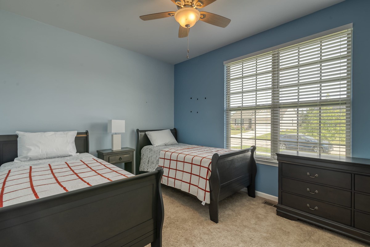 A cozy bedroom with two twin beds and blue walls.