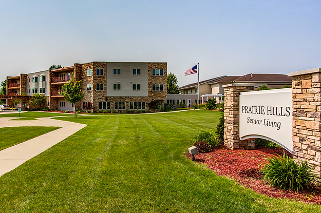 A senior apartment complex with a well-maintained green lawn and an American flag displayed outside.