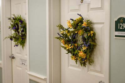 A decorative wreath made of yellow and blue flowers hangs on an interior door.
