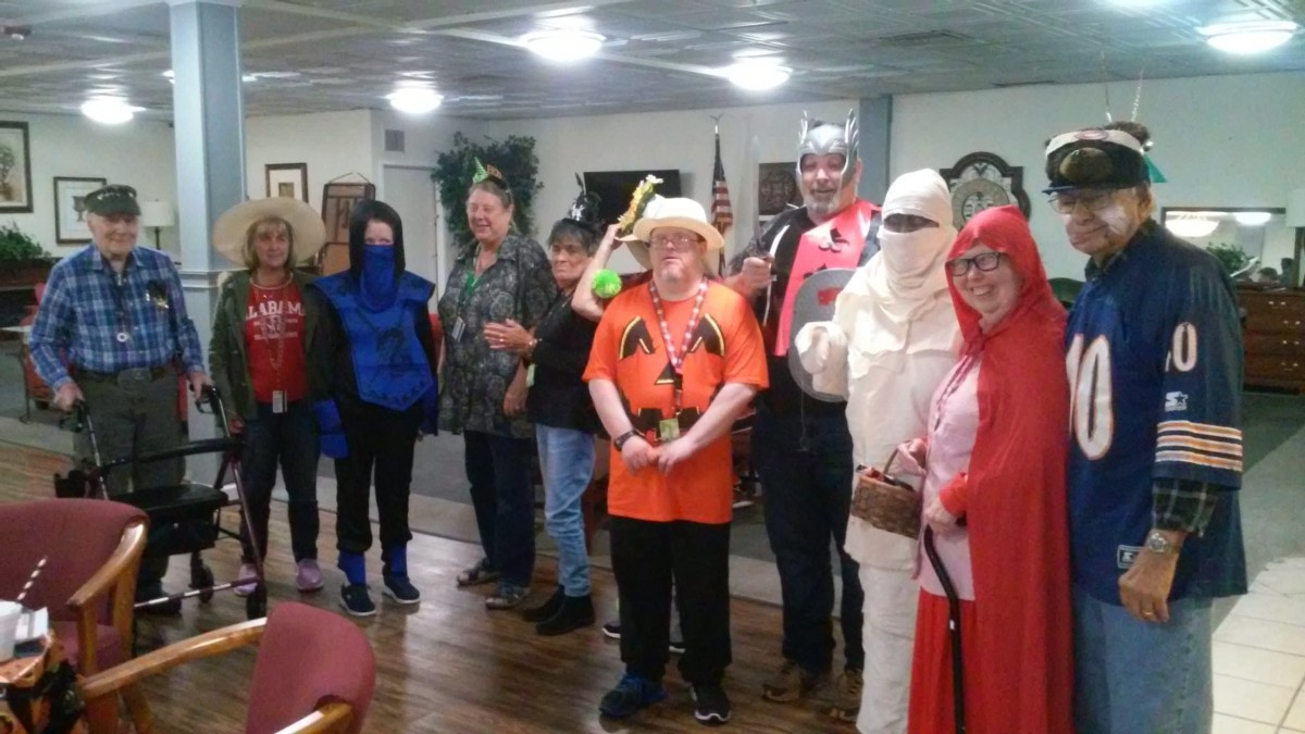 A group of people wearing Halloween costumes gathered indoors.