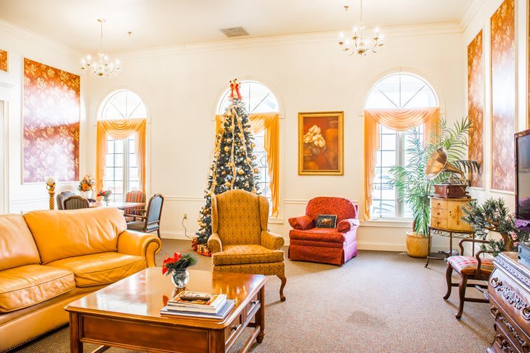 A cozy living room decorated for Christmas with a tree, armchairs, and warm lighting.