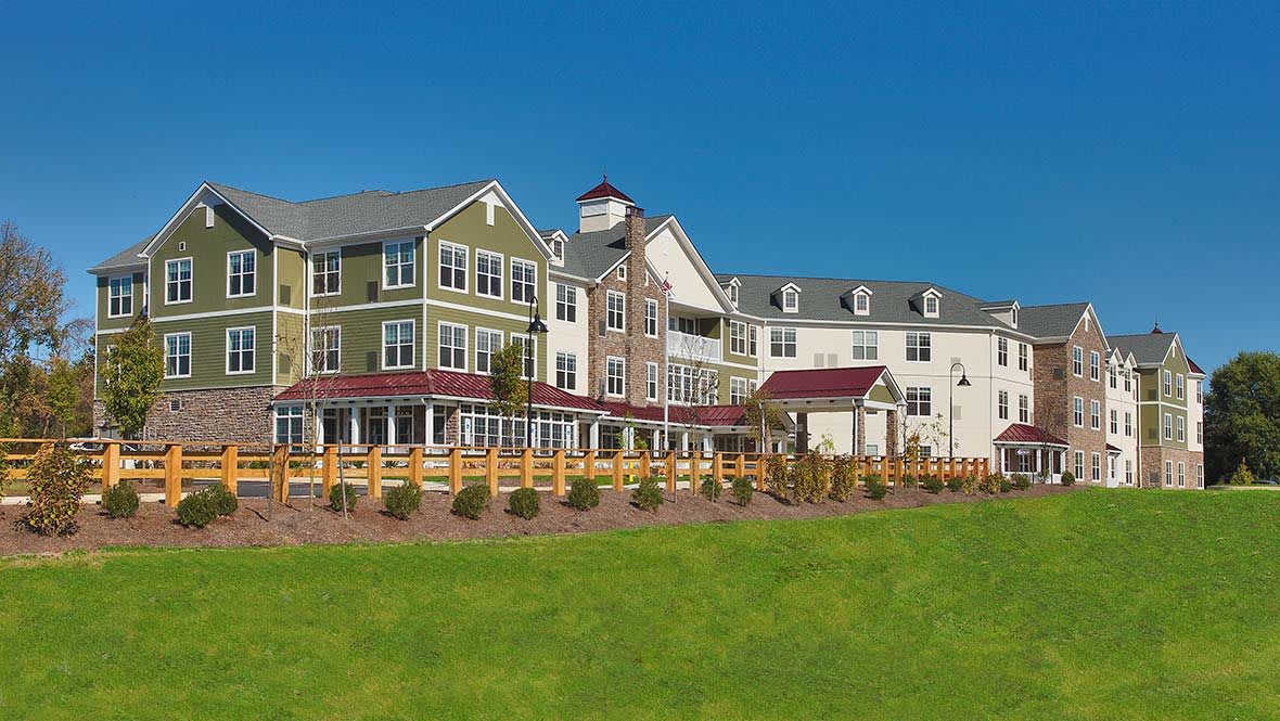 A modern residential building with a landscaped lawn under a clear blue sky.