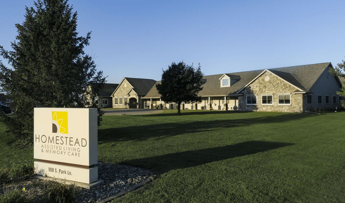 A large building with a lawn and a sign in front, set against a clear blue sky.
