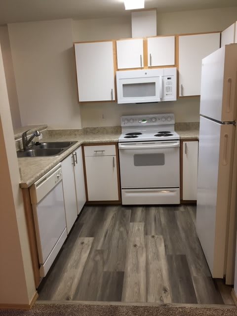 A compact kitchen featuring white appliances and modern flooring.