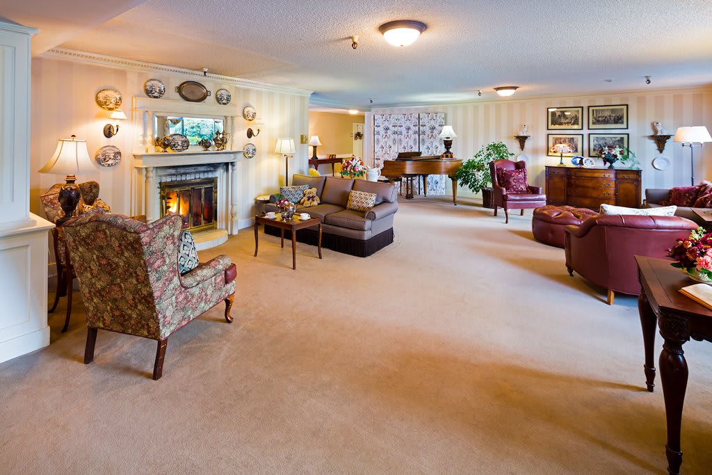 A spacious and cozy living room with a fireplace, piano, and elegant furniture.