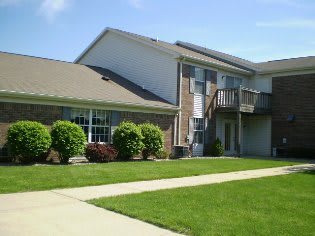 A suburban residential building with a well-maintained lawn and a balcony.