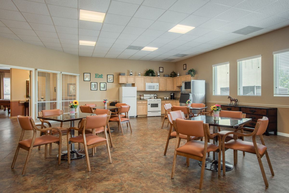 A communal kitchen and dining area with tables, chairs, and kitchen appliances.