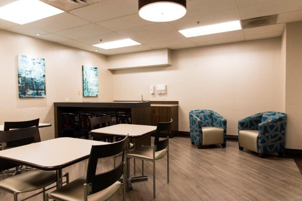A modern break room with tables, chairs, and a cozy lounge area.