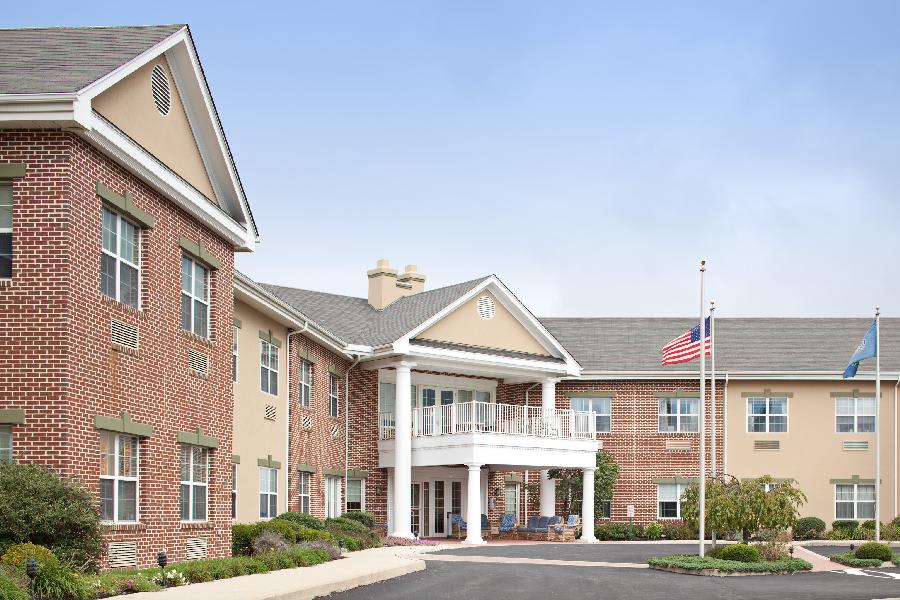 A brick building with a columned entrance and an American flag at the front.