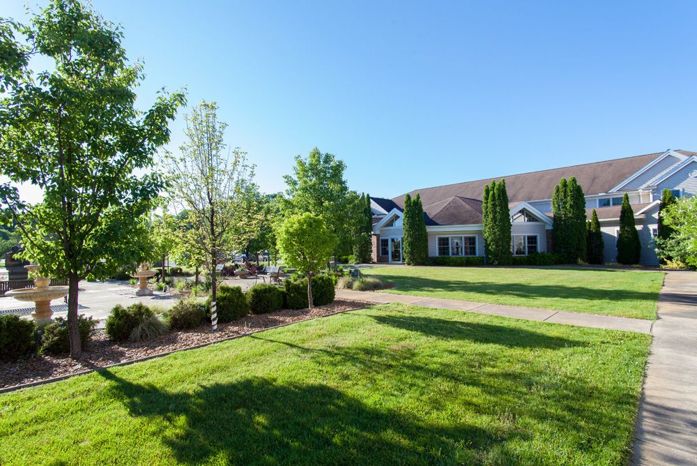 A scenic view of a building surrounded by lush greenery and trees on a sunny day.