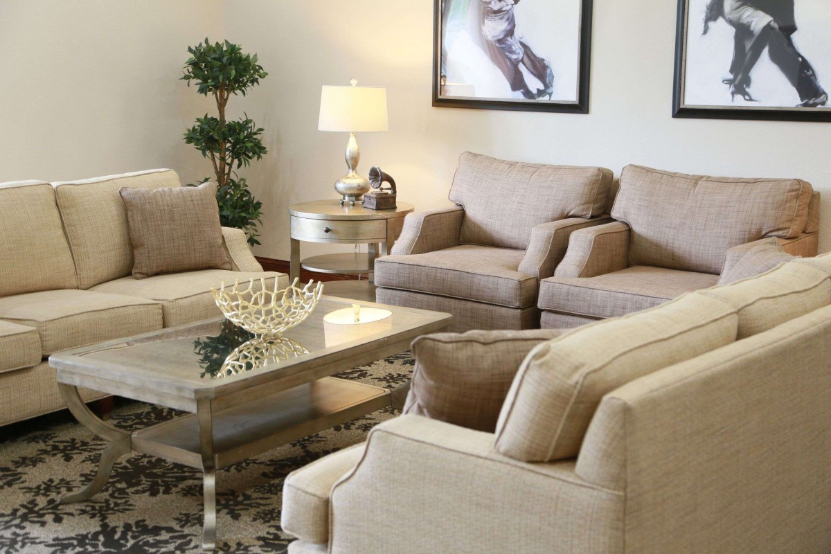 A stylish living room with beige sofas, a glass coffee table, and elegant decor.