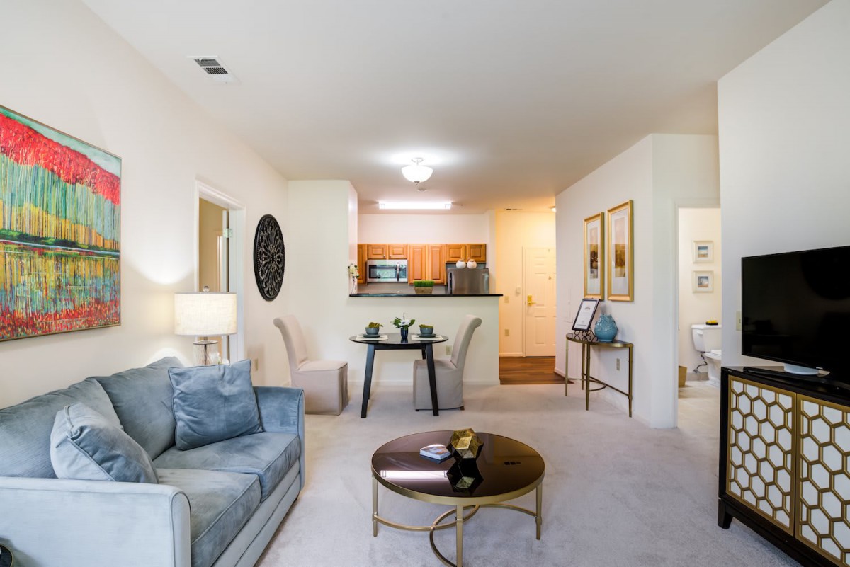 A cozy living room with a sofa, coffee table, and an adjoining kitchen area.