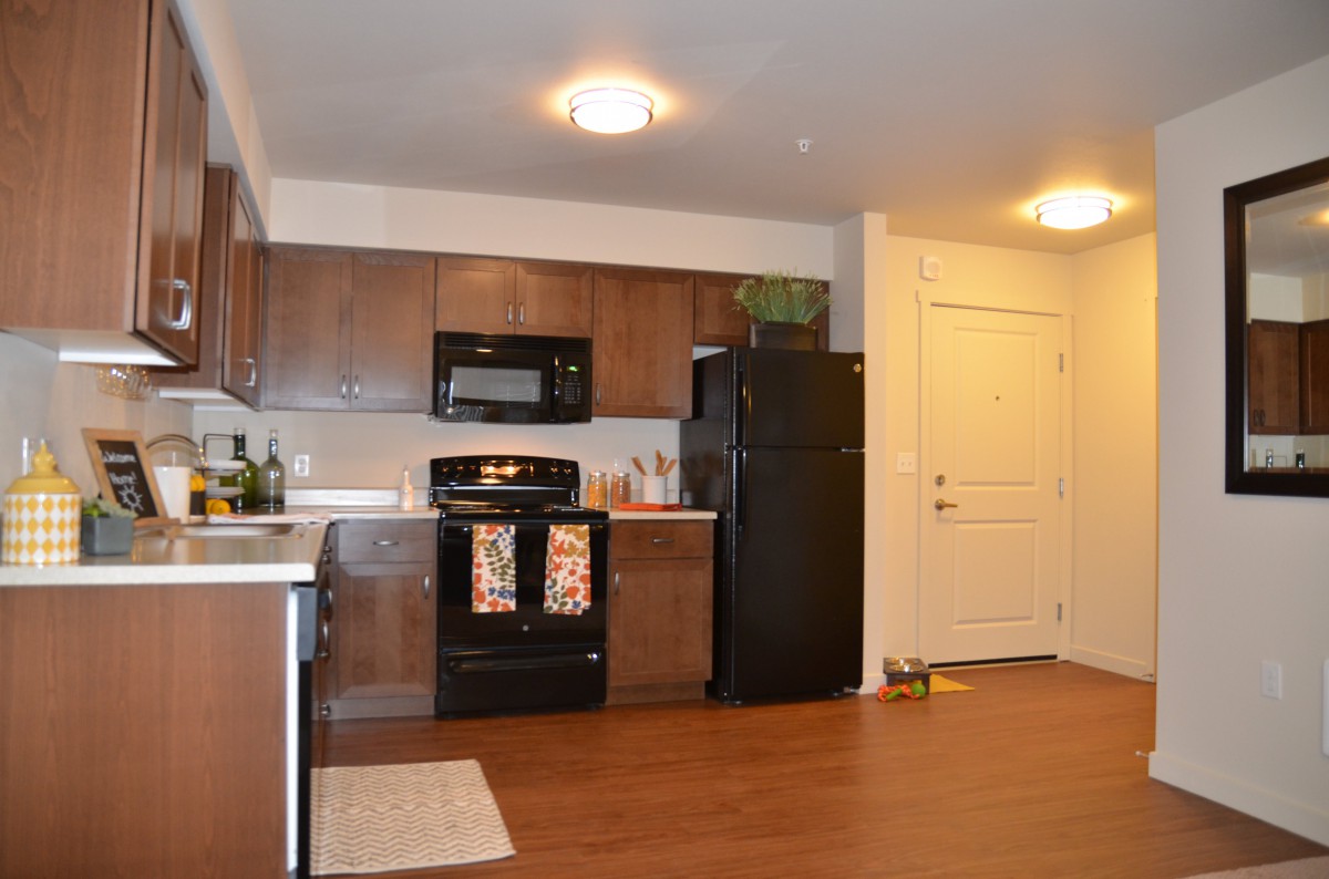 A modern kitchen with wooden cabinets, featuring a stove, microwave, and refrigerator.