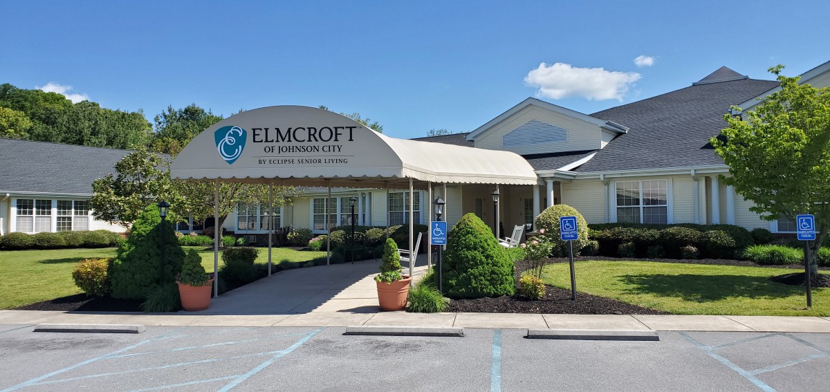 Entrance to a senior living facility with landscaped surroundings and a covered walkway.