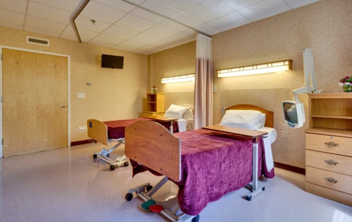 A hospital room with two beds and privacy curtains.