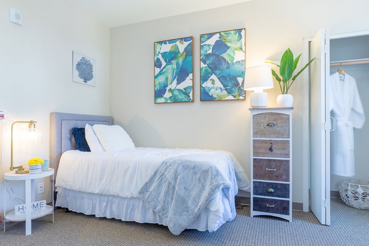 A modern bedroom featuring a neatly made bed, minimalist decor, and abstract artwork on the wall.