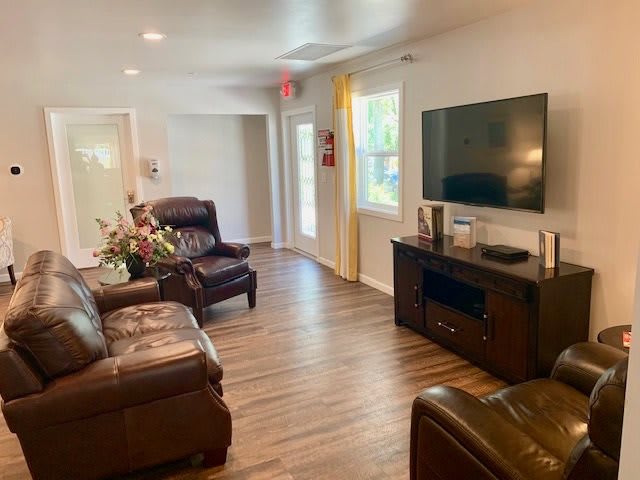 A cozy living room with leather sofas, a TV, and wooden flooring.