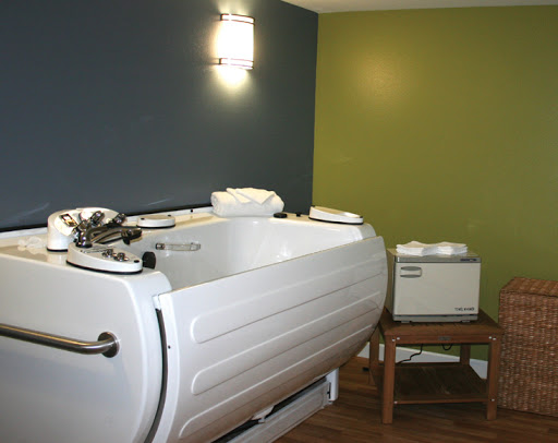 A modern spa treatment room featuring a therapeutic bathtub.