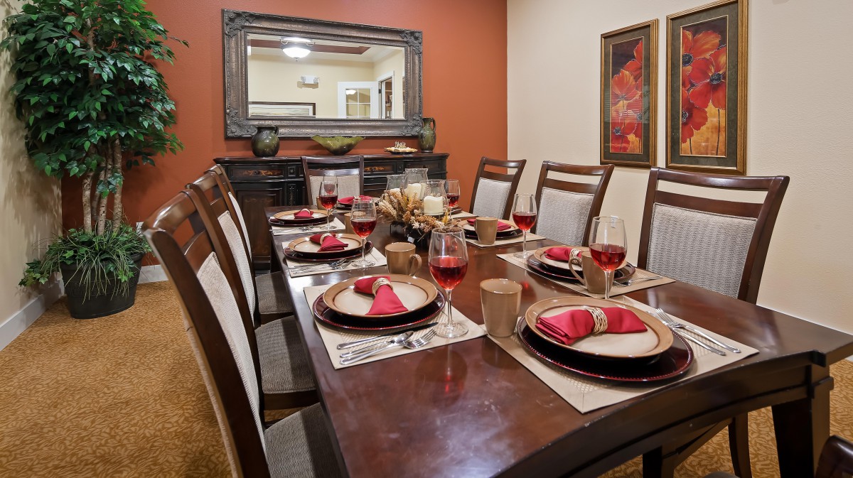 A beautifully set dining room table with red napkins and wine glasses.