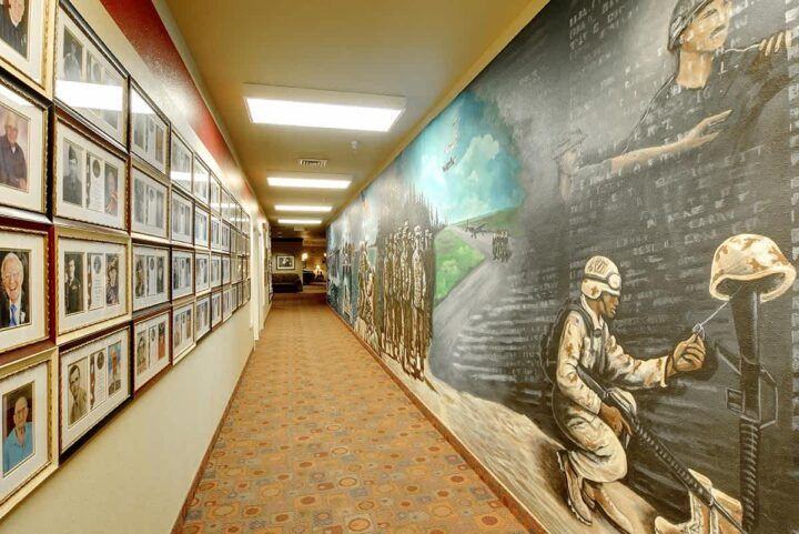 A hallway featuring a wall-length mural depicting soldiers and various framed photographs.