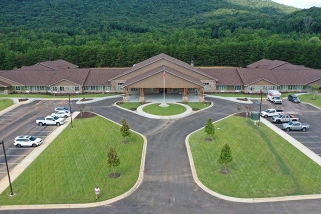 Aerial view of a building surrounded by greenery and parking spaces.