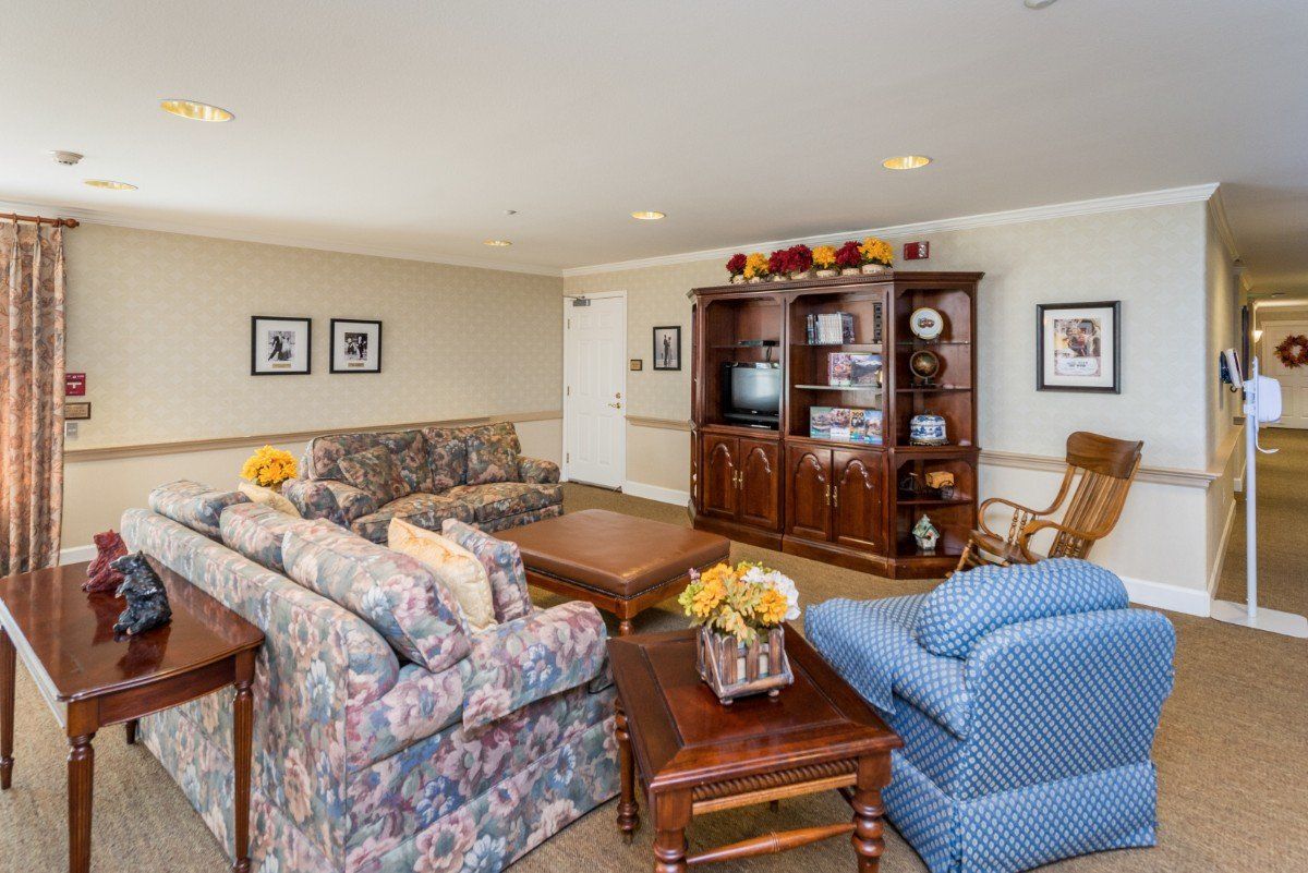 A cozy living room with floral sofas, a wooden coffee table, and an entertainment center housing a television.