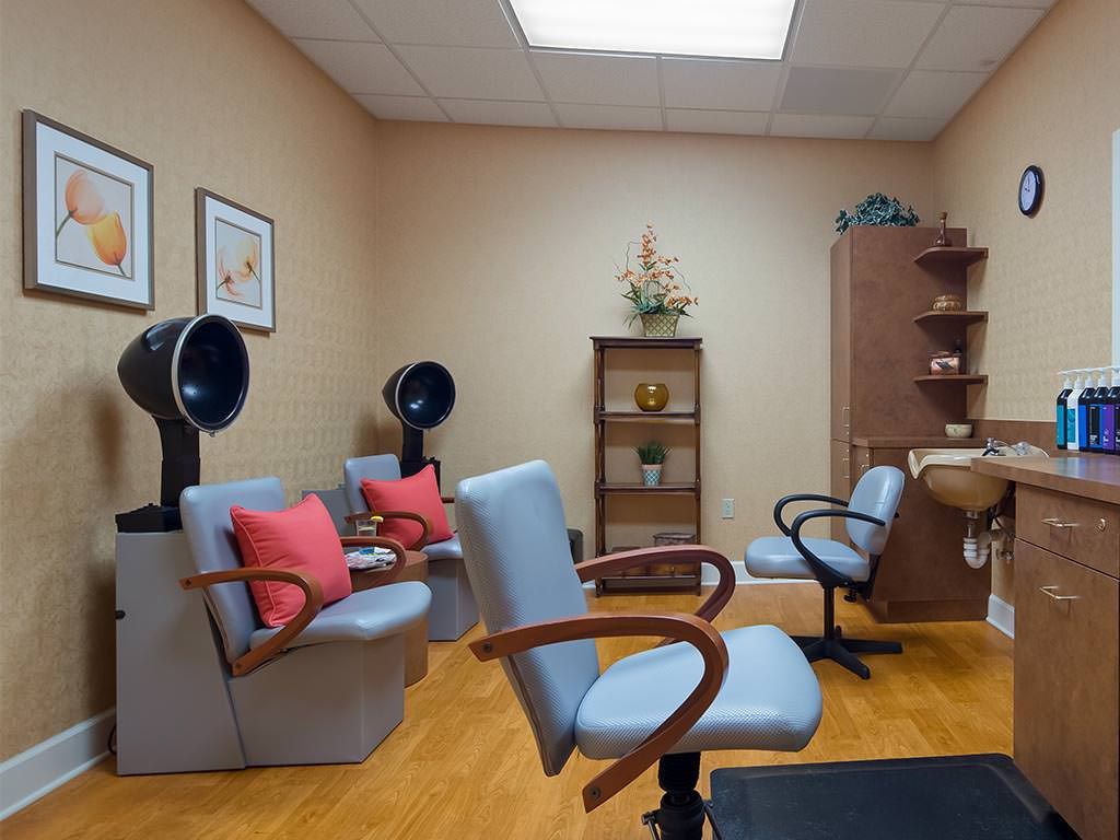 A cozy salon interior featuring blue chairs, hair dryers, and decorative elements on shelves.