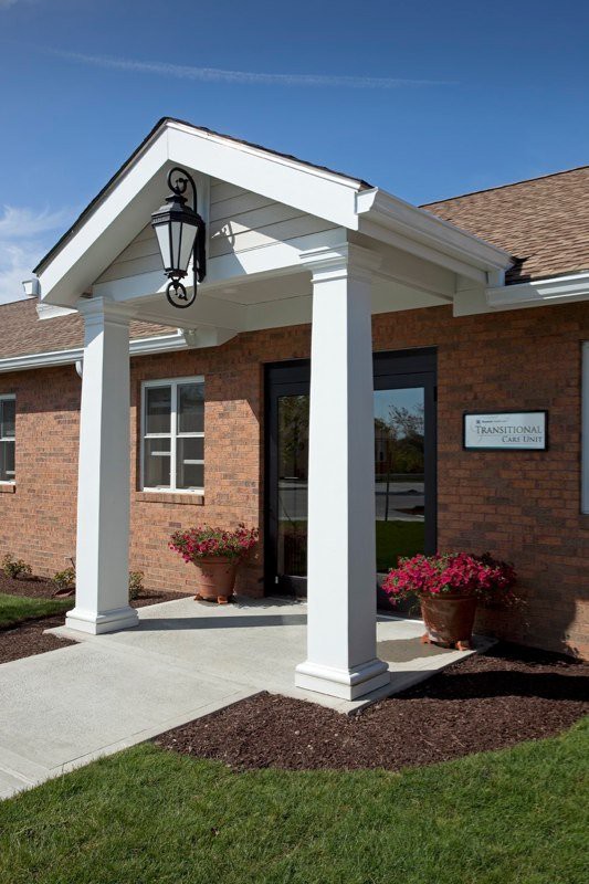 Entrance of a brick building with white columns and a hanging lantern.