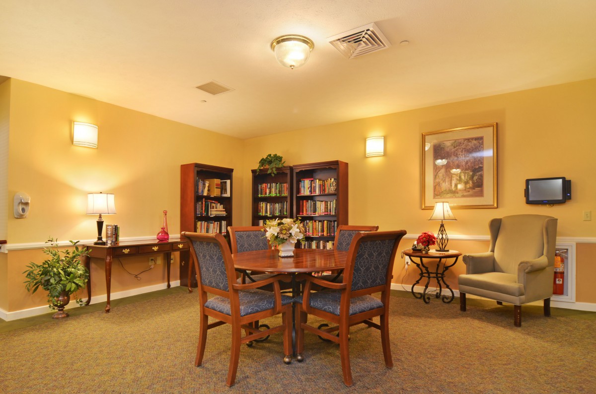 A cozy indoor reading area with bookshelves, a table, and chairs.