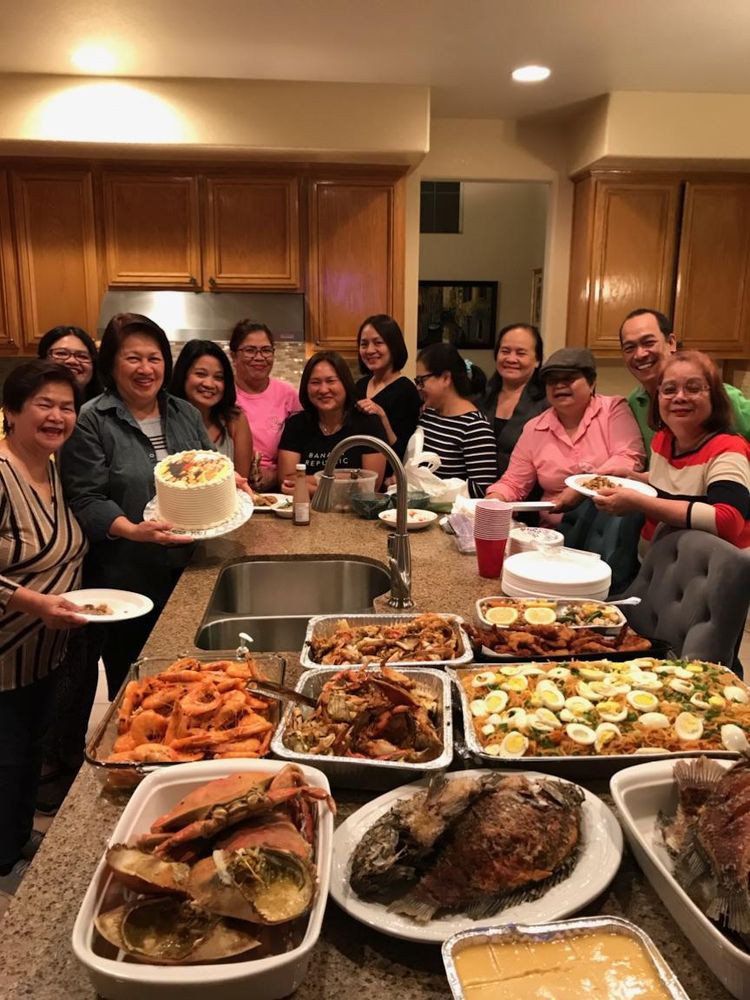 A group of people gathered in a kitchen with a variety of dishes for a celebration.