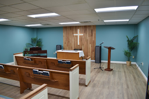 An interior view of a serene church setting with wooden benches and a focal cross.