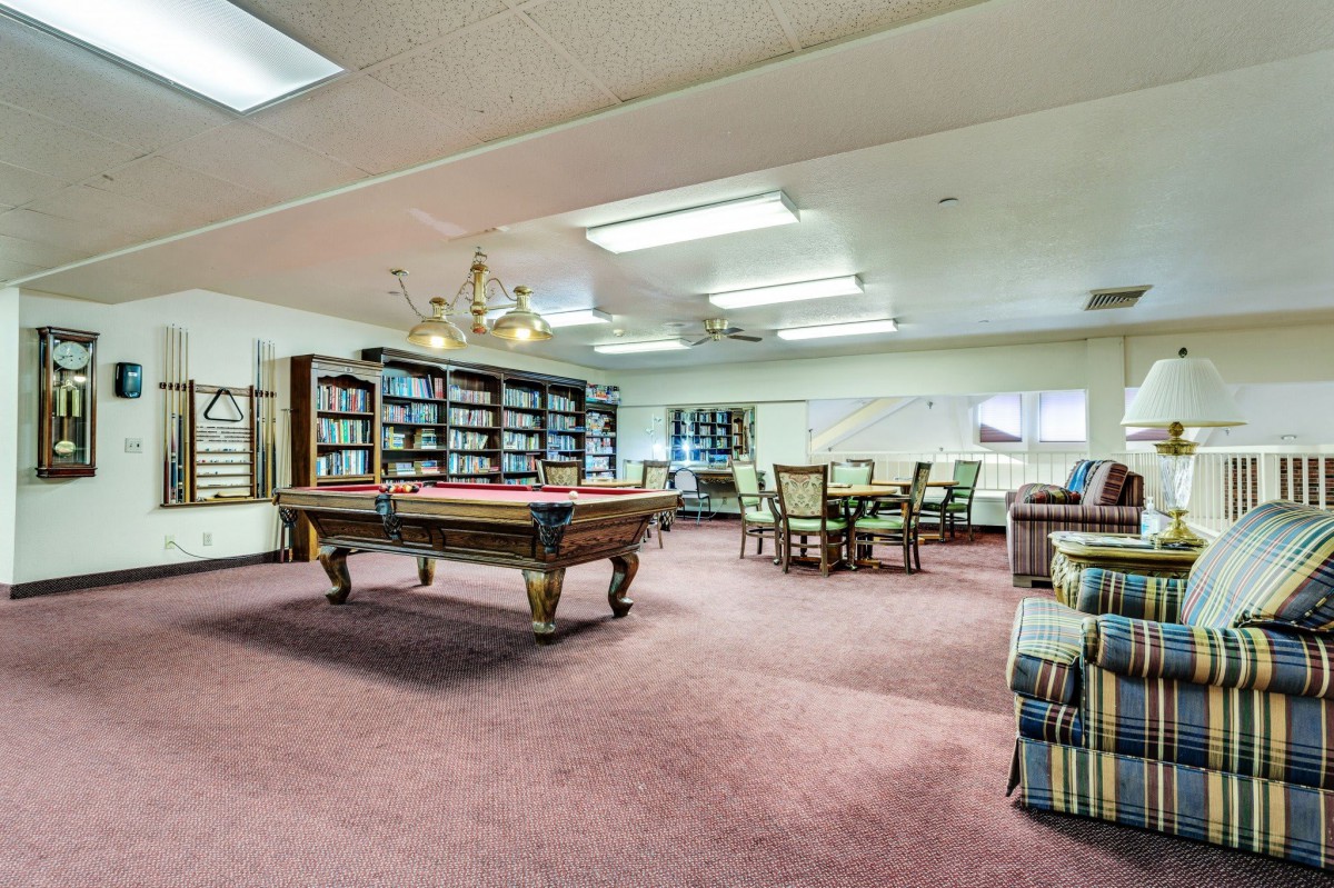 Spacious recreation room with a billiards table and bookshelves.