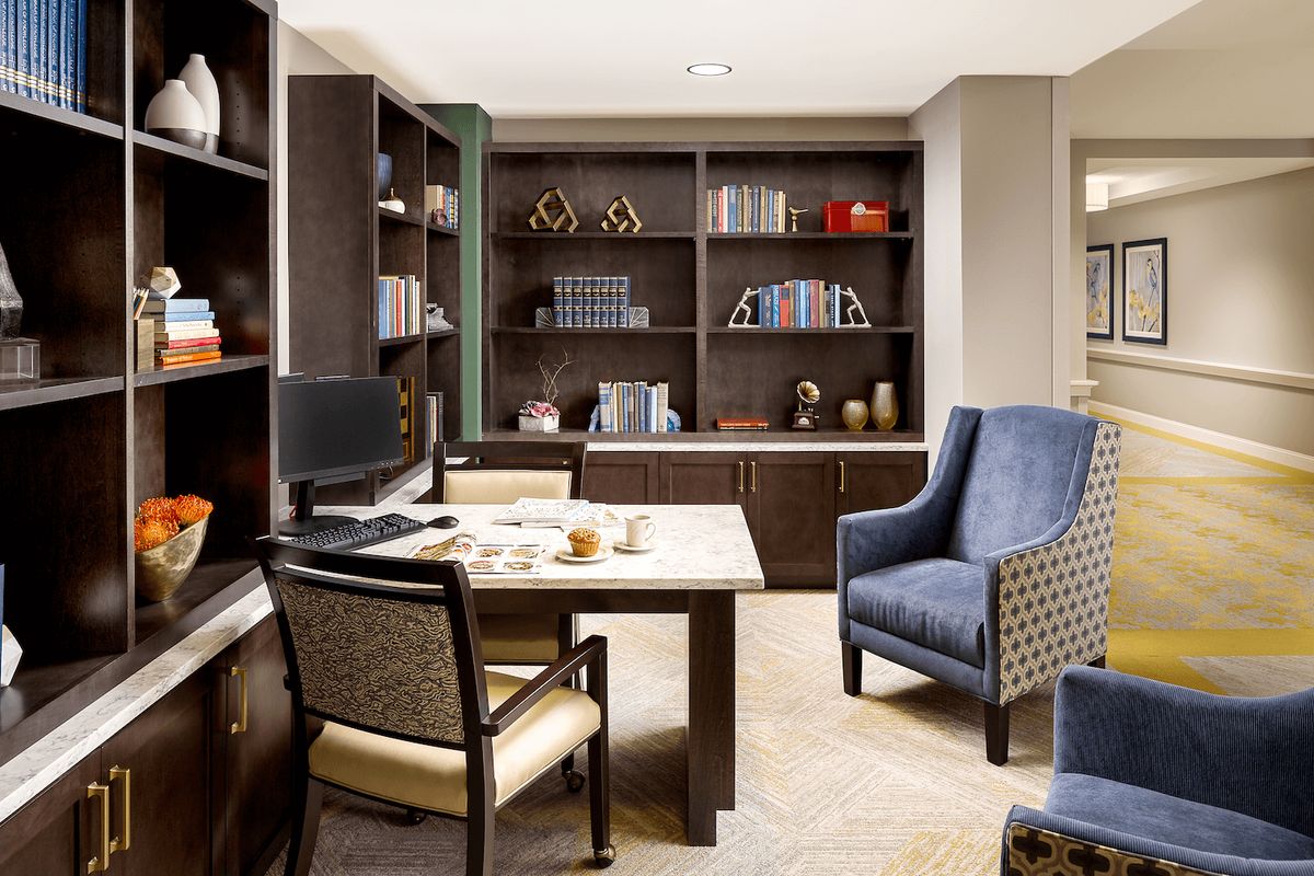 A modern office space featuring a desk, bookshelves, and comfortable seating.