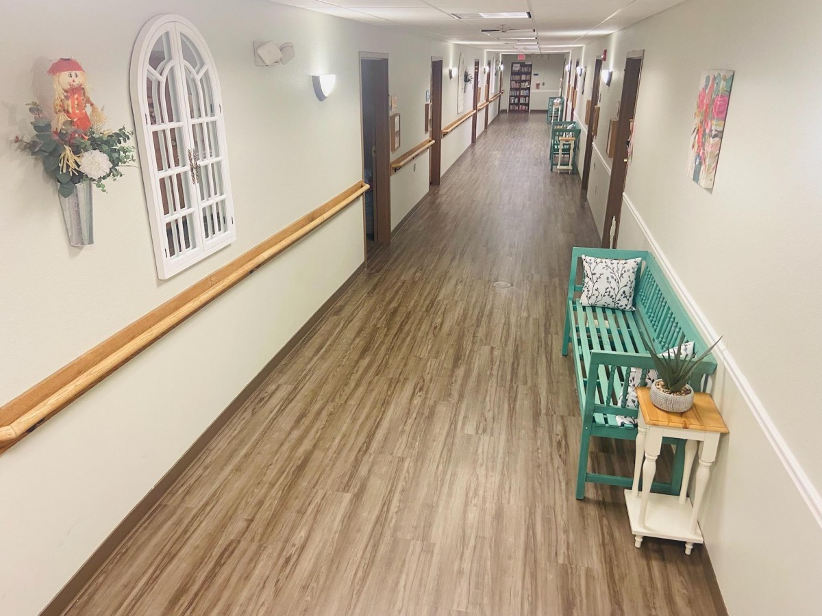 A long, well-lit hallway with wooden flooring and decorative furniture.