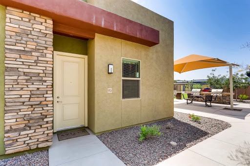 A modern residential entrance featuring a stylish door, landscaping, and outdoor seating.