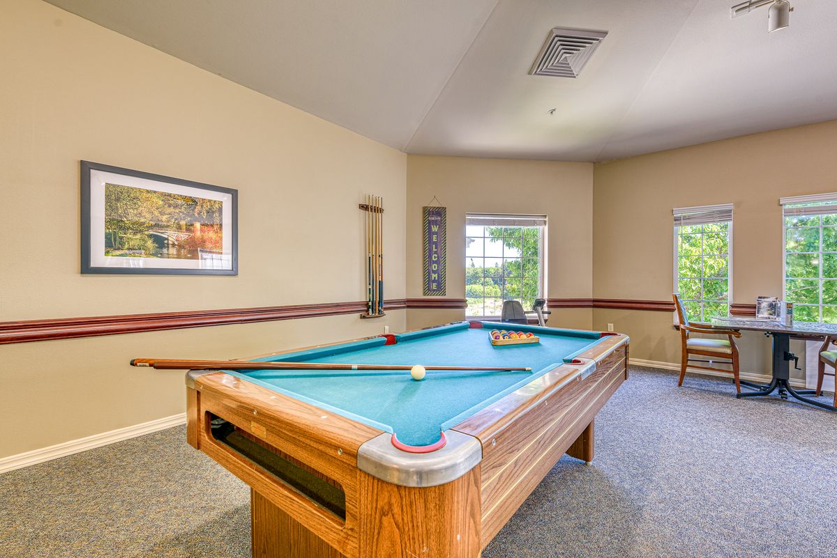 A cozy game room featuring a pool table next to large windows.