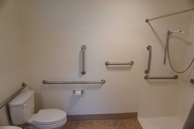 A bathroom with accessibility features including grab bars and a toilet.