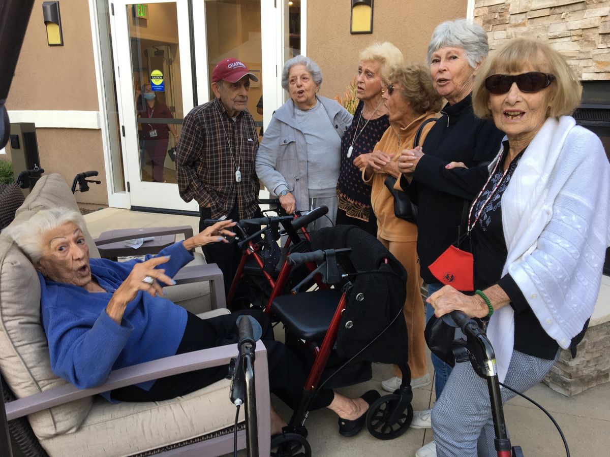 A group of elderly individuals engaged in conversation outdoors.